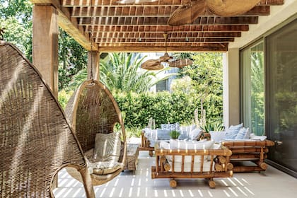 Ventiladores tipo cubanos (Mimbrero del Pilar). Hamacas colgantes (Compañía Nativa). Pérgola (Gabriel Konfederak). Sillones de bambú traídos de Uruguay con almohadones lisos y estampados en celeste. Banco hecho con un árbol recuperado (Verne Furniture).