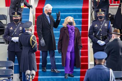 Vestida de púrpura, el color del bipartidismo, la ex candidata presidencial Hillary Clinton llega a la ceremonia de investidura de Biden junto con su marido el expresidente Bill Clinton