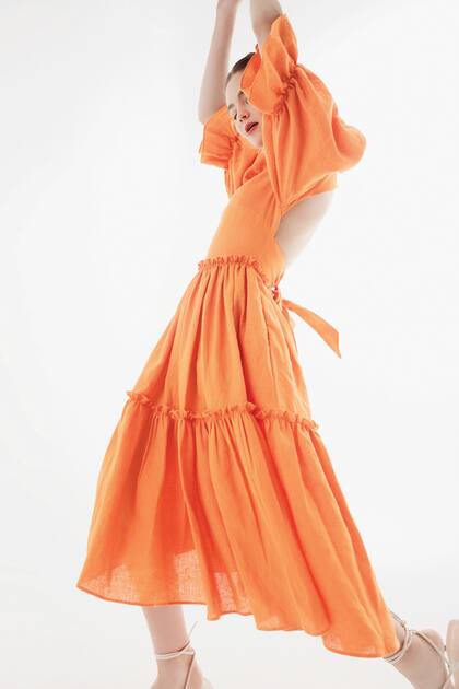 Vestido de lino escote en V con corte en cintura, falda de recortes de volados con bolsillos, mangas cortas con volumen y espalda descubierta (Valentina Karnoubi)