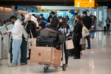 Viajeros hacen fila en un kiosko de Unide American Airlines en el Aeropuerto Internacional de Denver, el domingo 26 de diciembre de 2021. (AP Foto/David Zalubowski)