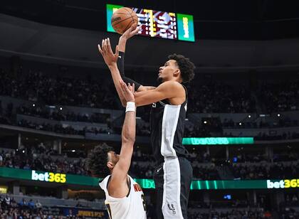 Victor Wembanyama, derecha, de los Spurs de San Antonio, se alza sobre Jamal Murray, de los Nuggets de Denver, para tomar un tiro