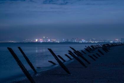 Viejas barricadas anti-aterrizaje se alinean en la costa a lo largo de una playa en Kinmen, una isla periférica de Taiwán, el 18 de noviembre de 2021. La ciudad china de Xiamen es visible en la distancia. (Lam Yik Fei/The New York Times)
