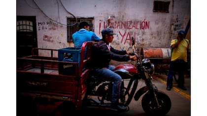 Una moto pasa adelante de un grafiti que dice "¡Urbanización ya!"