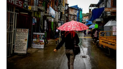 Una mujer camina a través de la Villa 31 un día nublado