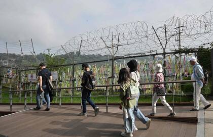 Visitantes caminan junto a una cerca militar en el parque de paz Imjingak en la ciudad fronteriza de Paju el 19 de julio de 2023.