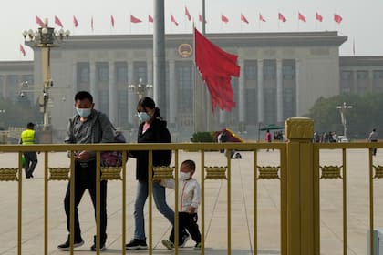 Visitantes con barbijo caminan en la Plaza Tiananmen previo al Congreso del PCC