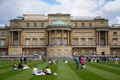 Visitantes disfrutan de un picnic en el césped durante una visita previa por el Jardín del Palacio de Buckingham, la residencia oficial de la reina Isabel II en Londres, que se abre al público el viernes