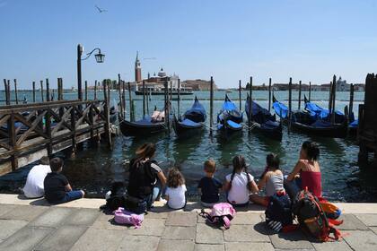Visitantes italianos observando las embarcaciones en Venecia.