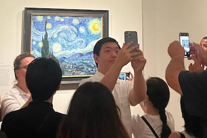 Visitantes sacándose fotos junto a la obra "La noche estrellada", de Vincent van Gogh, en la muestra temporal Van Gogh's Cypresse, en el MET de Nueva York, 2023
