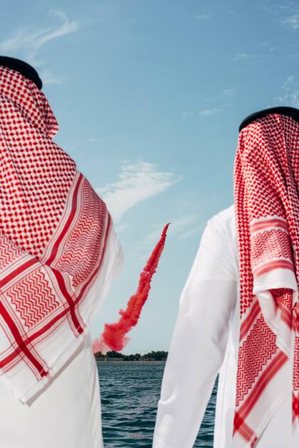 Visitantes saudíes observan el espectáculo aéreo durante la feria. Expo IDEX, Abu Dabi, Emiratos Árabes Unidos, 2019