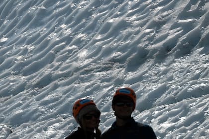Visitantes se toman una foto junto a una pared de hielo texturizado en el glaciar Matanuska