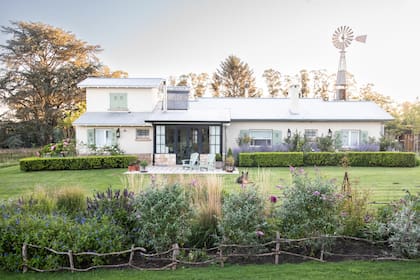Vista de la casa con un cantero formal contra ella y un cantero bien suelto por delante