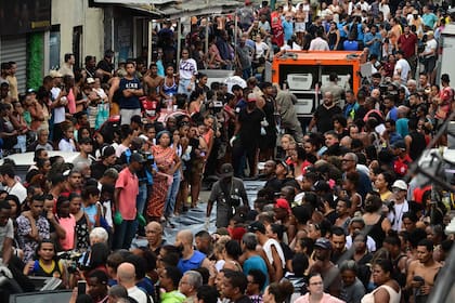 Vista de la gente amontonada alrededor de los cuerpos que están siendo cargados en el camión de la morgue