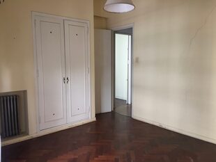 Vista del dormitorio con el antiguo parquet oscuro bajo capas de cera de años.