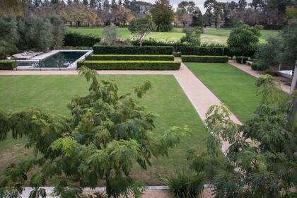 Vista del jardín con el gran plano de césped y las líneas de buxus.