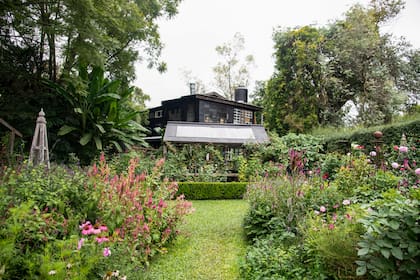 Vista general del jardín con sus amplios canteros de herbáceas. Más atrás, uno de los invernáculos y su propia casa. Todo es parte de La Flor Azul.