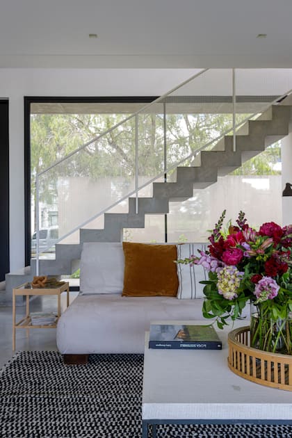 Vista hacia la calle, con la escalera de hormigón como perfil sólido y dinámico. Arreglo floral de Alejandra Raimúndez