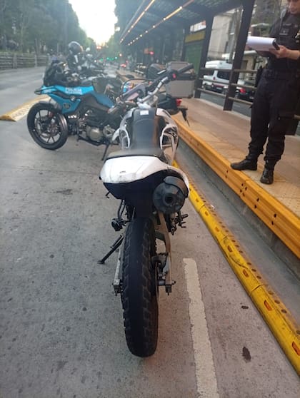 Vista trasera de la moto Yamaha secuestrada, estacionada sobre la avenida Almirante Brown junto a patrullas policiales