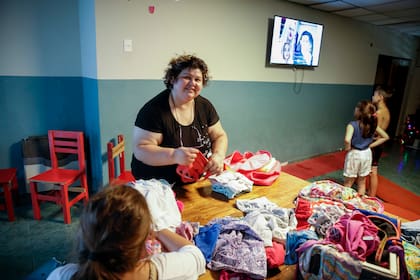 Viviana ordena la ropa de las niñas y los niños, junto a una voluntaria que la ayuda; en el hogar siempre se necesitan donaciones 