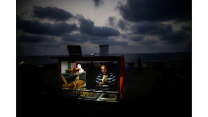 Un vendedor ambulante en la playa usa baterías para iluminar