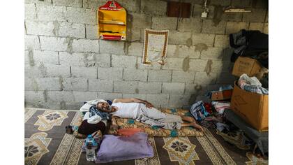Un hombre usa una bandeja de plástico para ventilarse durante un corte de luz en su casa en Khan Younis, en el sur de la Franja de Gaza