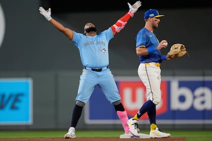 Vladimir Guerrero Jr. (27), izquierda, de los Azulejos de Toronto, celebra después de batear un doble durante la octava entrada del juego de béisbol de Grandes Ligas ante los Mellizos de Minnesota, el viernes 6 de junio de 2025. en Minneapolis. (AP Foto/Abbie Parr)