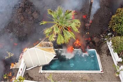 Lenta pero implacablemente la lava entra en la piscina de una casa que ya desapareció