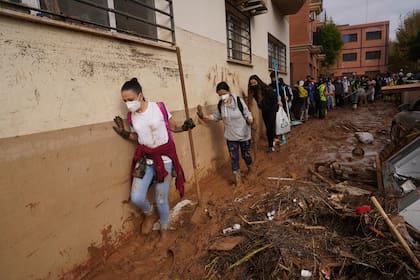 Voluntarios caminan entre el lodo para colaborar en las tareas de limpieza tras las inundaciones que arrasaron Massanassa, a las afueras de Valencia, el 2 de noviembre de 2024. (AP Foto/Alberto Saiz)