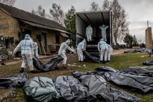 Voluntarios cargando a los muertos en un camión en Bucha, Ucrania.