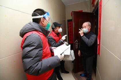 Voluntarios de la comunidad visitan a los residentes para conocer sus necesidades en un conjunto residencial, en la ciudad de Xi'an, en la provincia noroccidental china de Shaanxi. (Chinatopix vía AP)