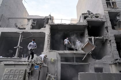 Voluntarios retiran escombros de un edificio residencial dañado cuando una comisaría cercana fue atacada el viernes en un ataque de Israel y Estados Unidos en Teherán, Irán, el domingo 15 de marzo de 2026. (AP Foto/Vahid Salemi)