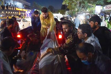 Voluntarios y personal médico descargan cuerpos de una camioneta fuera de un hospital después de que dos poderosas explosiones mataron al menos a una decena de personas, fuera del aeropuerto de Kabul 