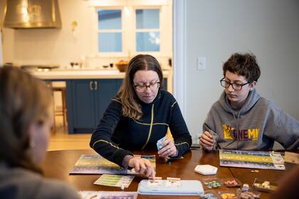 Wes Sumner, de 16 años, a la derecha, juega un juego de mesa con su familia en su casa en Minneapolis, el 12 de febrero de 2021