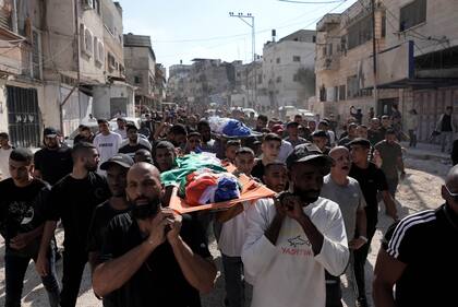 La gente asiste a una ceremonia fúnebre por los palestinos que perdieron la vida en un ataque aéreo israelí contra una cafetería en el campo de refugiados de Tulkarem, Cisjordania