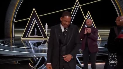 Will Smith acaba de ganar el Oscar al mejor actor y agradecerlo entre lágrimas. Lo aplaude, detrás, John Travolta