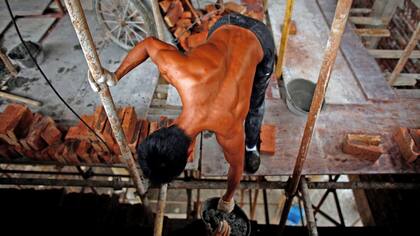 Shi Shenwei, entrega un cubo de cemento a un colega, en un templo budista en el pueblo de Huangshan, cerca de Quanzhou, provincia de Fujian, China