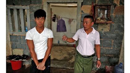 Shi Shenwei (izq), escucha a su tío y capataz Shi Lijia, en una antigua casa de campo que sirve como dormitorio para los trabajadores en una construcción cercana a un templo budista en el pueblo de Huangshan, cerca de Quanzhou, provincia de Fujian, China,