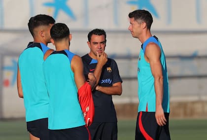 Xavi Hernandez observa un entrenamiento, con Robert Lewandowski adelante