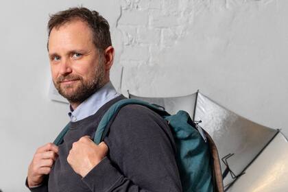 Tomás Saraceno en su estudio de Berlín, con la mochila que permite transportar "esculturas solares" y un paraguas diseñado para cocinar con energía solar