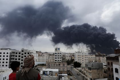 Yemeníes observan las columnas de humo causadas por los ataques aéreos israelíes contra una central energética y el Aeropuerto de Saná, el martes 6 de mayo de 2025, en Saná, Yemen. (AP Foto/Osamah Abdulrahman)