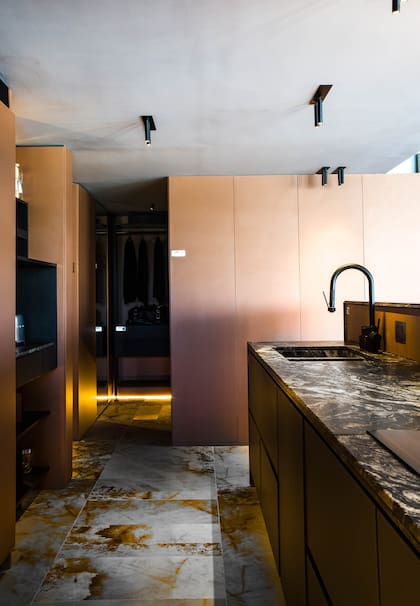 Yendo hacia el otro extremo de la cocina, nos dirijimos a los espacios privados. La bacha conformada está realizada con el mismo granito Amadeus (De Stefano) trabajado por Giannetta Mármoles. Grifería Augusta Pro en Black (FV).