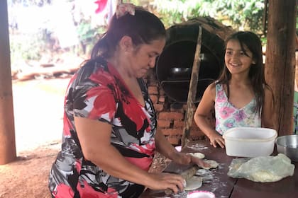 Yenifer Mierez ayuda a su mamá a hacer las tortas fritas que después van a repartir entre los chicos del barrio; el jarro de leche funciona en el quincho de su casa