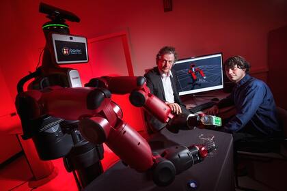 Yiannis Aloimonos de la Universidad de Maryland posa junto a Baxter, el robot empleado para implementar el sistema que permite identificar objetos y generar nuevos comportamientos de uso