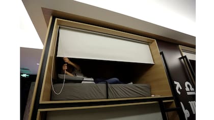 Zhang Shuang Jie, un ingeniero de la empresa Baishan, baja una cortina mientras se prepara para dormir alrededor de la medianoche en un cuarto individual en la oficina