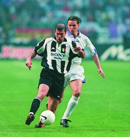 Zidane lleva la pelota; Redondo lo persigue