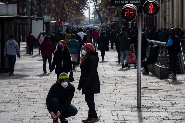 Personas con máscaras faciales caminan en la Plaza de Armas en Santiago, el 6 de julio de 2020, en medio de la pandemia de coronavirus