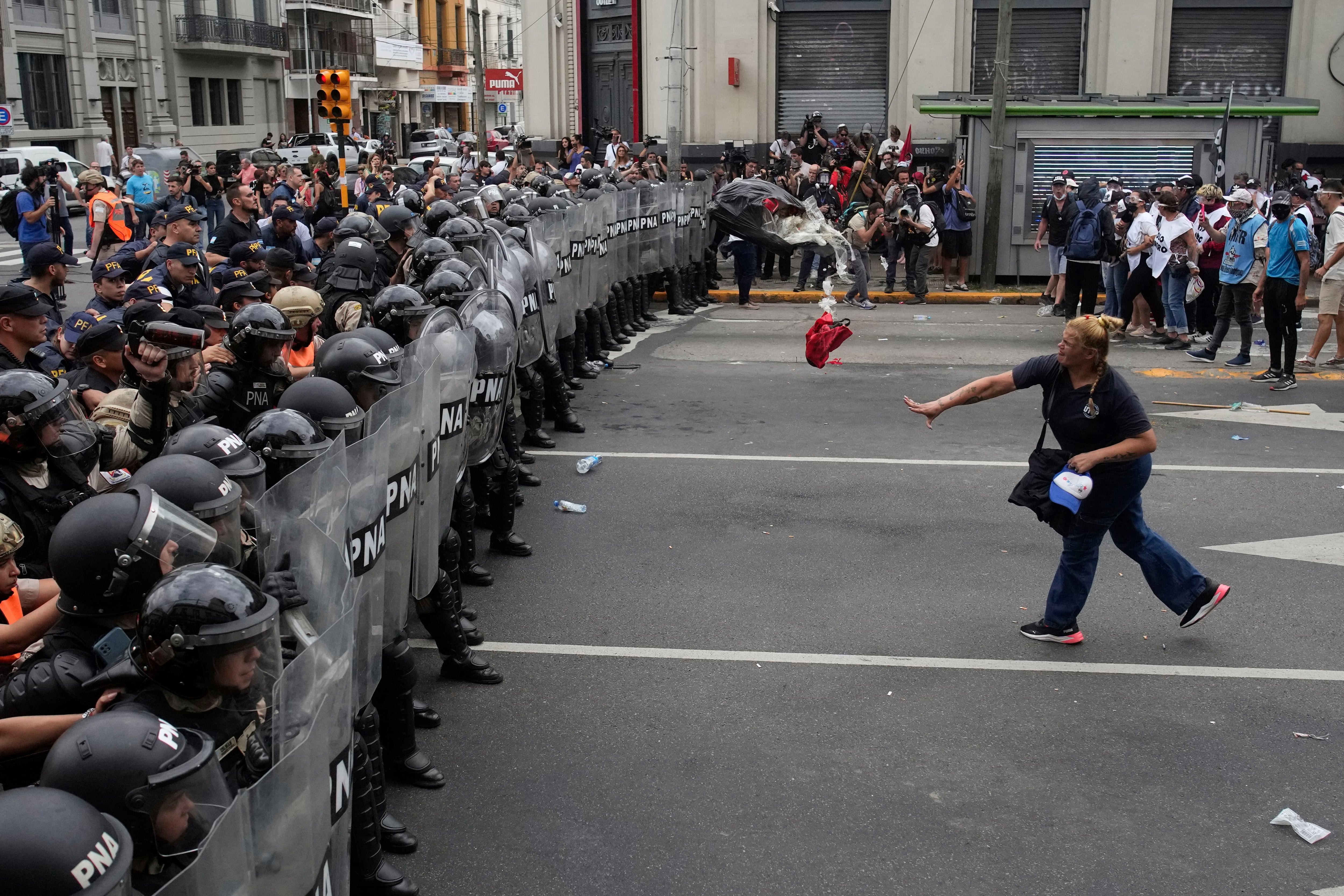 Una mujer arroja una bolsa de basura a la policía que bloquea una manifestación contra la escasez de alimentos en los comedores populares y las reformas económicas propuestas por el presidente Javier Milei