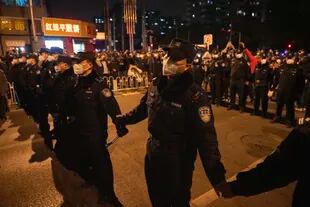 Policías chinos forman una línea para detener la marcha de los manifestantes en Pekín, el domingo 27 de noviembre de 2022.