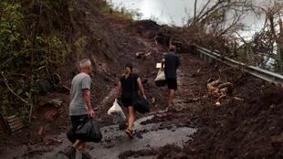 Residentes caminan por una carretera destruida en San Lorenzo semanas después de que el huracán María golpeara Puerto Rico