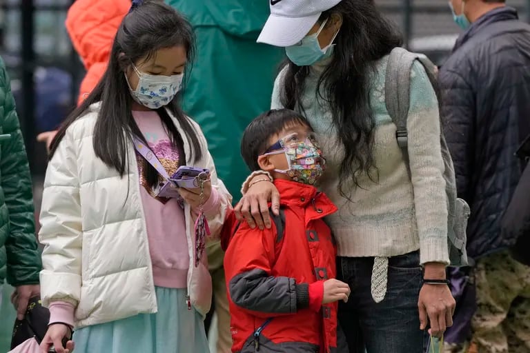 Una familia hace fila para hacerse la prueba del coronavirus en un centro de pruebas temporal en Hong Kong, el jueves 17 de febrero de 2022. Hong Kong reportó el jueves 6.116 nuevas infecciones por coronavirus, ya que los hospitales de la ciudad alcanzaron el 90% de su capacidad y las instalaciones de cuarentena están en su límite, dijeron las autoridades. (AP Photo/Kin Cheung)
